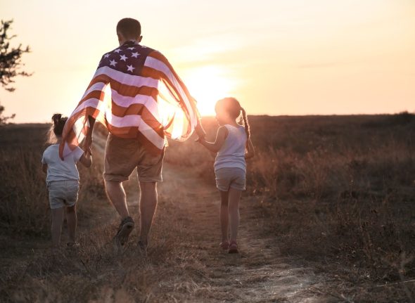 A happy family with an American flag at sunset.